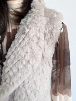 Detalle cercano del chaleco de pelo sintético beige, con textura mullida y suave.