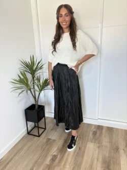 Look urbano con falda polipiel negra midi y zapatillas deportivas.