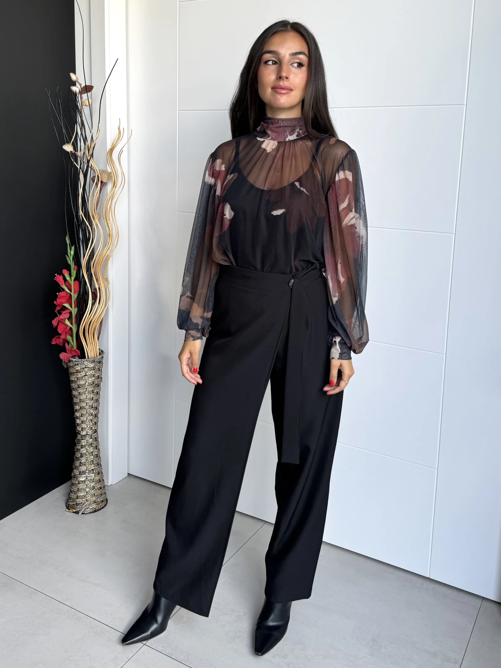 Modelo de frente con pantalón negro de tiro alto cruzado y pierna