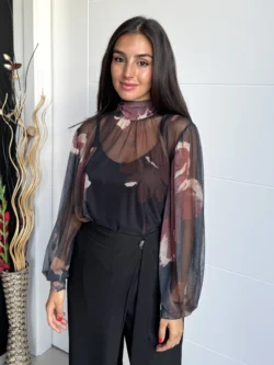 Mujer con blusa de tul negro transparente con estampado floral en tonos burdeos y nude, vista frontal