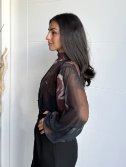 Mujer de perfil luciendo blusa de tul negra con estampado floral