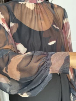 Primer plano de la tela de tul transparente con flores burdeos y nude sobre fondo negro