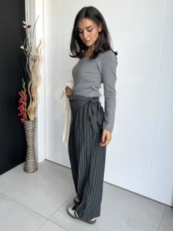 Mujer con pantalón ancho corte fluido gris y fajín anudado.