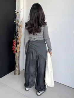 Parte trasera del pantalón fluido gris con rayas y fajín anudado en la cintura.