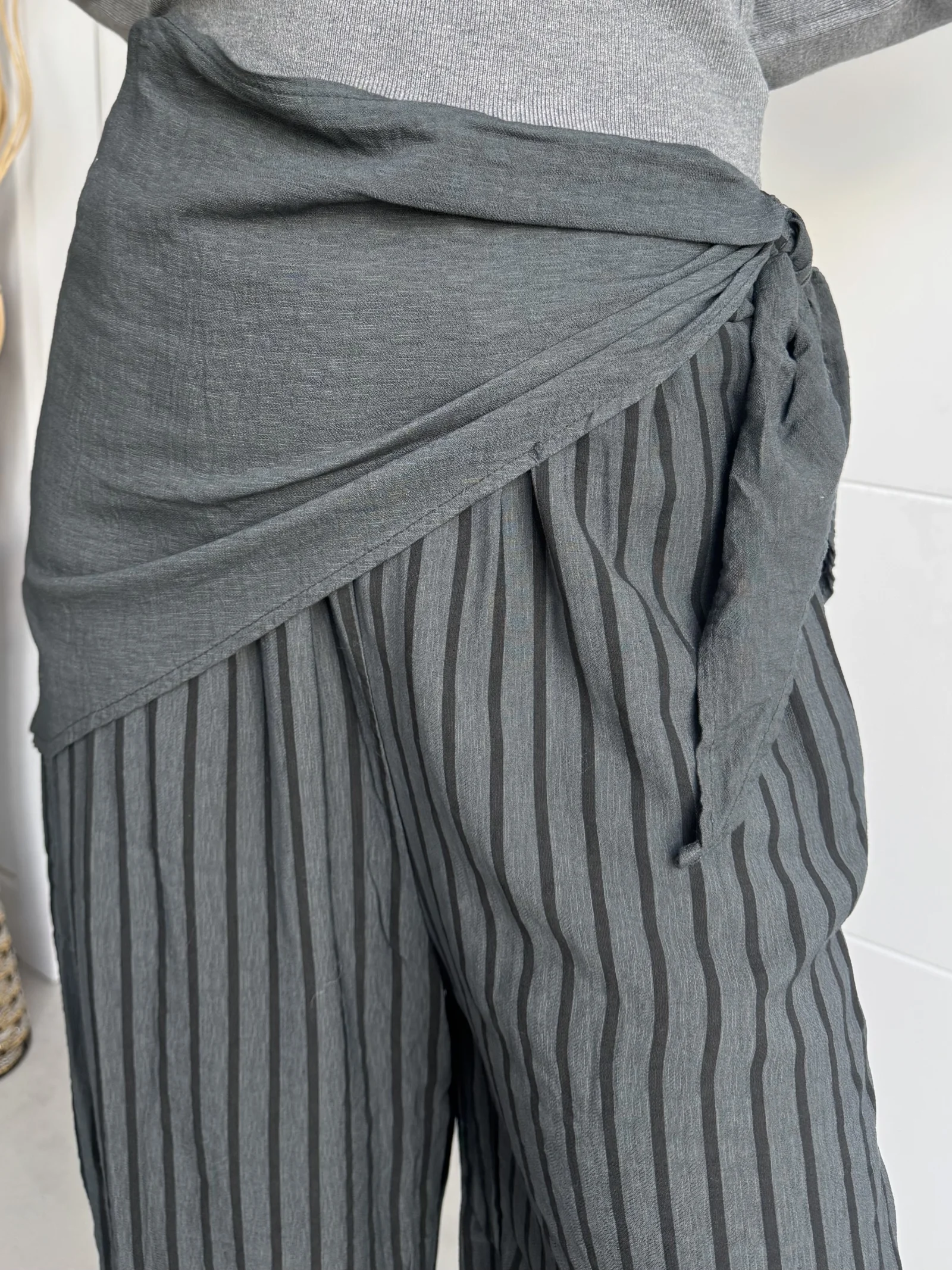 Cintura del pantalón fluido gris a rayas con fajín cruzado y lazada.