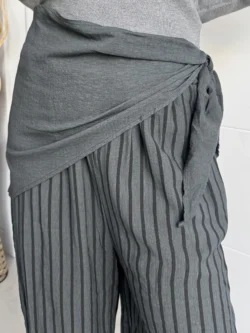 Cintura del pantalón fluido gris a rayas con fajín cruzado y lazada.