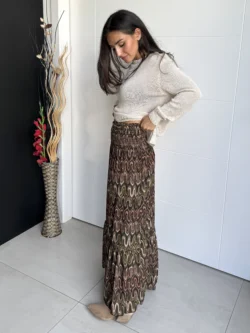 Mujer con falda larga estampada geométrica vista lateral, combinada con jersey claro.