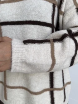 Detalle de manga larga en jersey cuadros beige y marrón.