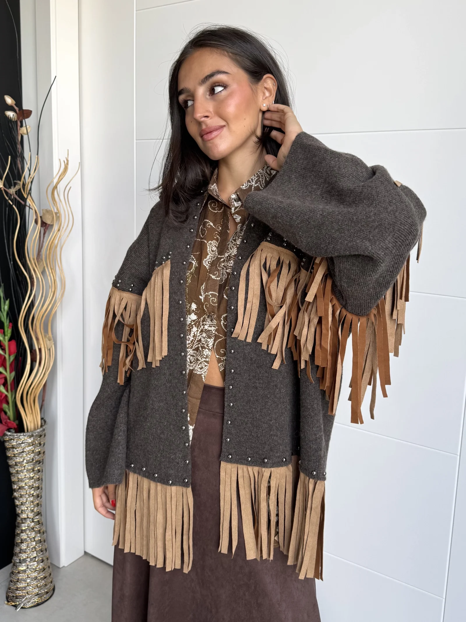 Mujer de pie luciendo kimono con flecos tonos tierras y camel y tachuelas, corte oversize.