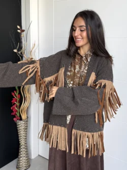Mujer con brazos extendidos mostrando el movimiento de los flecos en chaqueta marrón.
