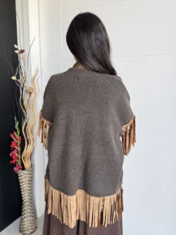 Mujer de espaldas con chaqueta marrón oversize con flecos camel.