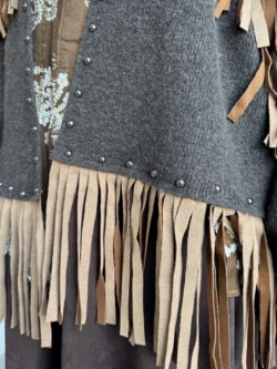 Close-up de flecos camel en contraste con tejido marrón y tachuelas metálicas.