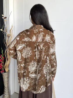 Mujer de espaldas con camisa marrón oversize de estampado floral blanco.