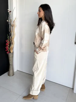 Pantalón beige satinado ancho visto de perfil con bajo vuelto