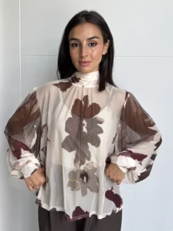 Mujer con blusa de gasa beige semitransparente estampada en tonos tierra, corte suelto.