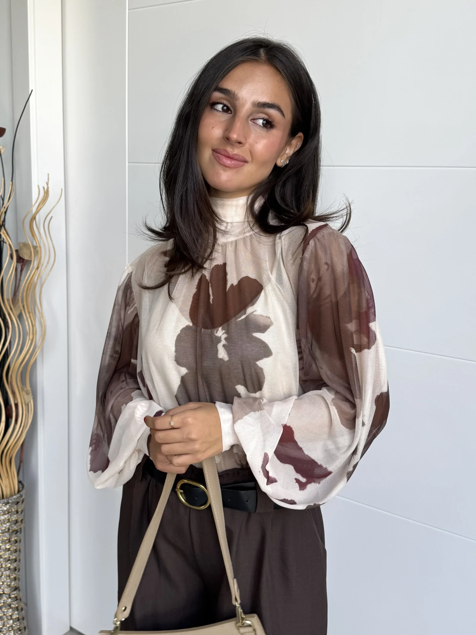 Modelo con blusa gasa floral estampada floral marrón y borgoña, mangas globo y cuello fruncido con lazada.