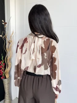 Vista trasera de blusa de gasa floral con lazada al cuello y manga globo.