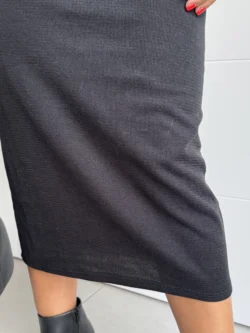 Primer plano del bajo acabado en vestido negro midi de punto canalé.